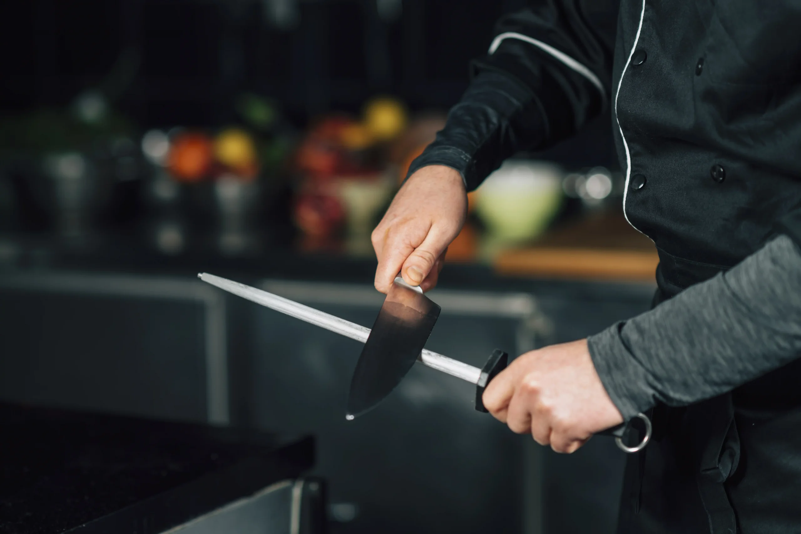 Chef cuisinier aiguisant un couteau à l'aide d'un fusil à aiguiser